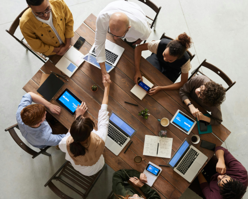Réunion d'équipe en agence de marketing digital autour d'une table, collaboration stratégique avec ordinateurs portables et tablettes – CreatixHT